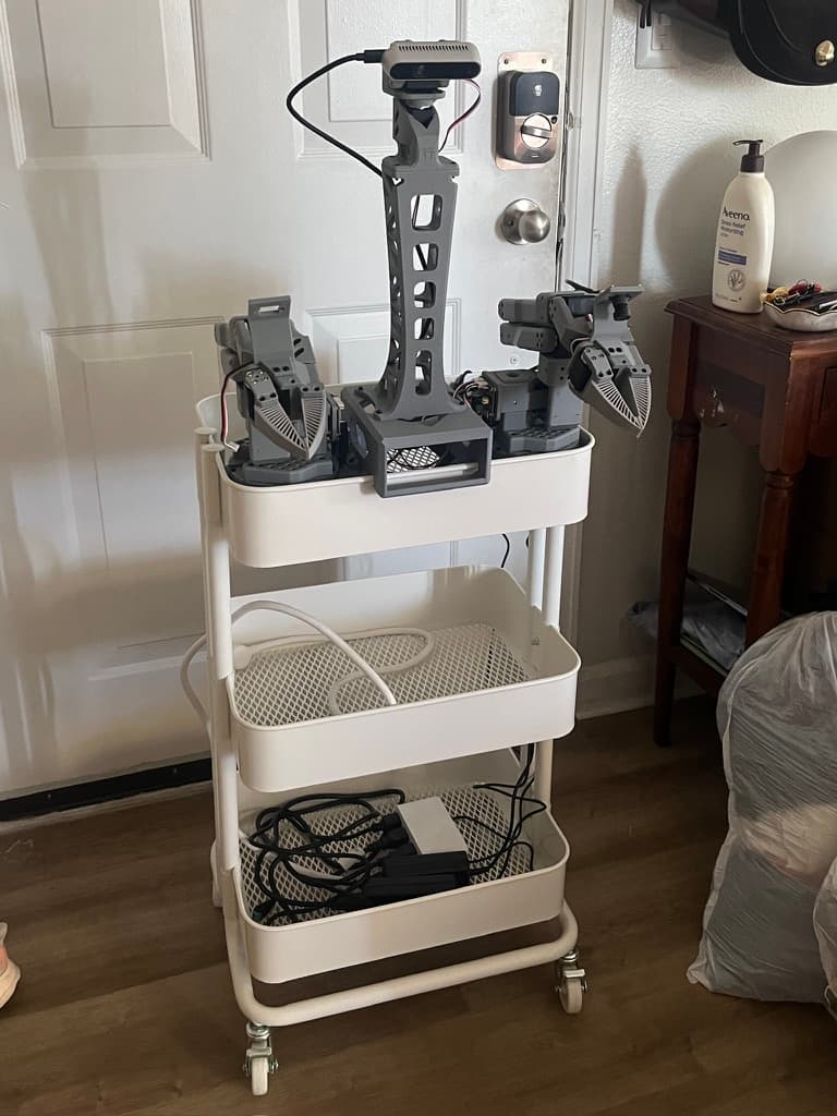 Dual-arm xLeRobot with grippers and a camera mast mounted on a rolling cart